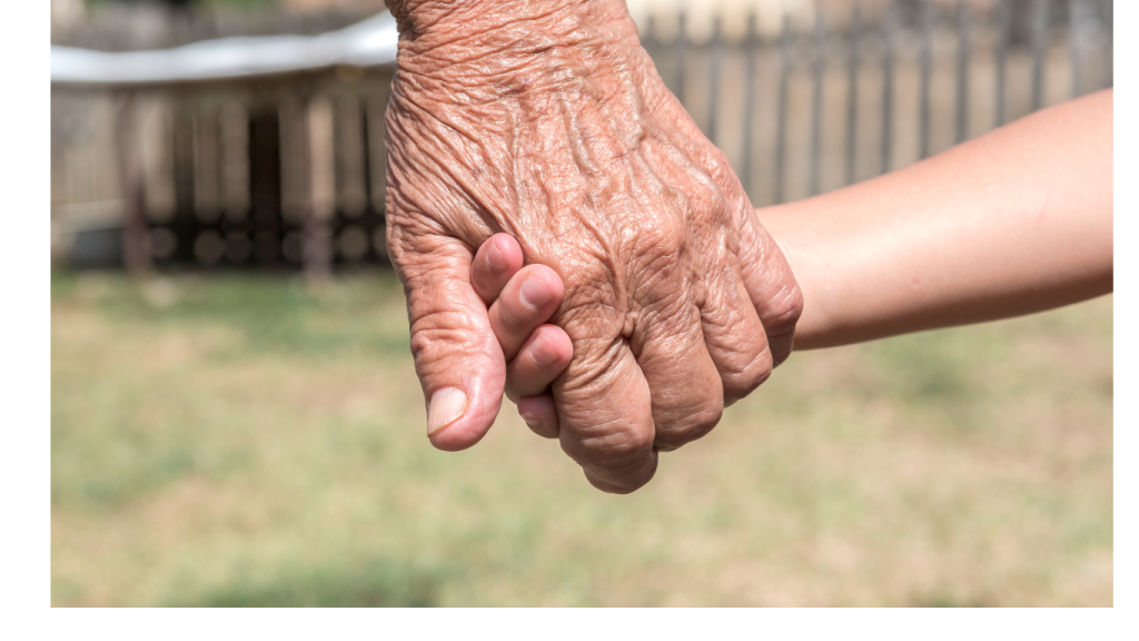 A weathered and wrinkled hand holds a small child hand.